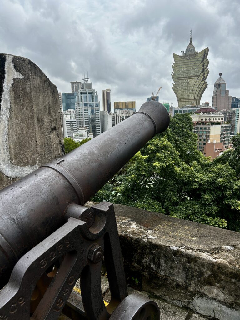 widok z ruin fortu w Makau, widoczna armata i najsłynniejsze kasyno symbol miasta z kwiatem lotosu